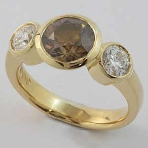 A rubbed-in set three stone ring featuring an Australian Argyle cognac diamond in the centre.