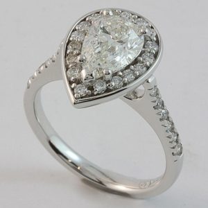 18 carat white gold pear shaped halo engagement ring with diamond set shoulders.